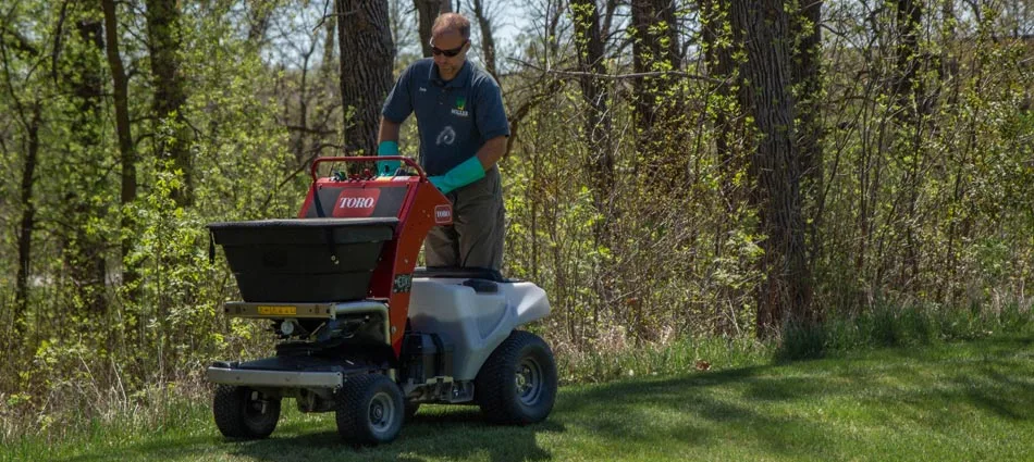 Miller Yard Care & Construction professional treating and fertilizing a lawn in Detroit Lakes, MN.
