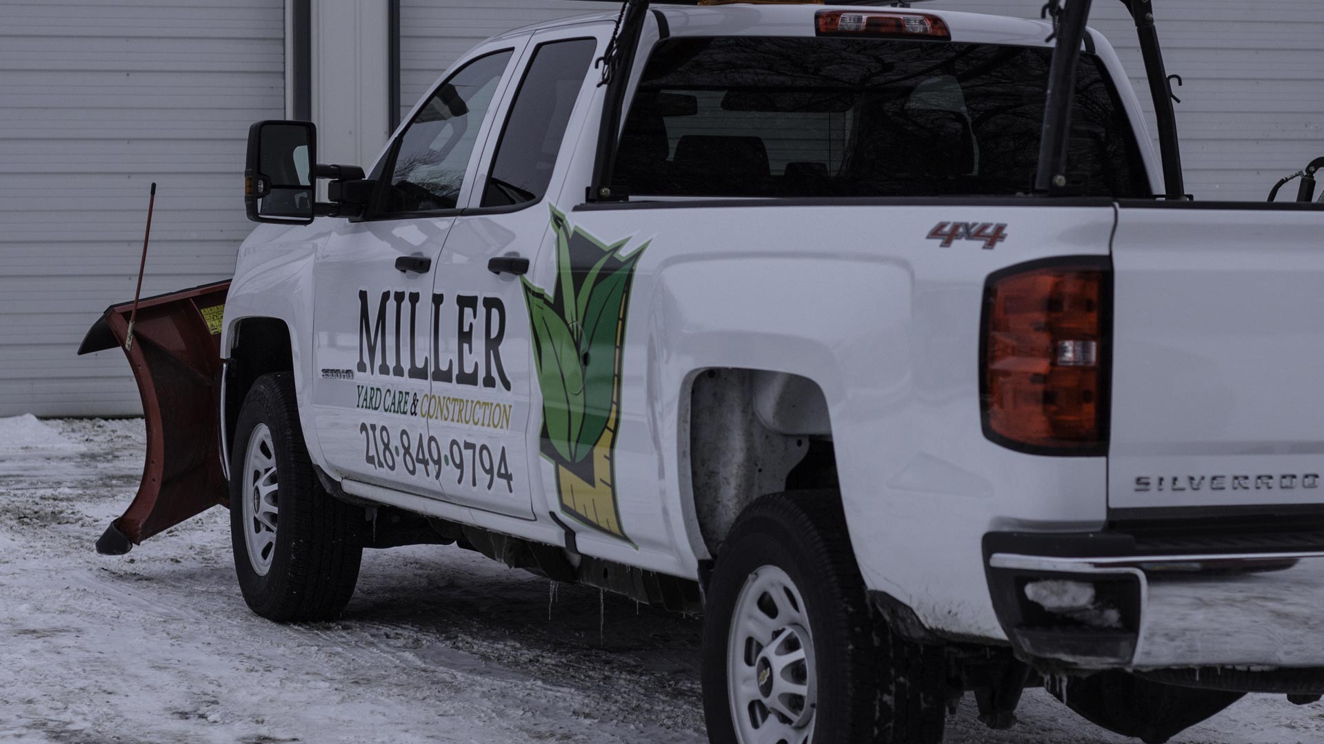 Miller Yard Care & Construction company truck with a snow plow on the front in preparation for snow removal services.