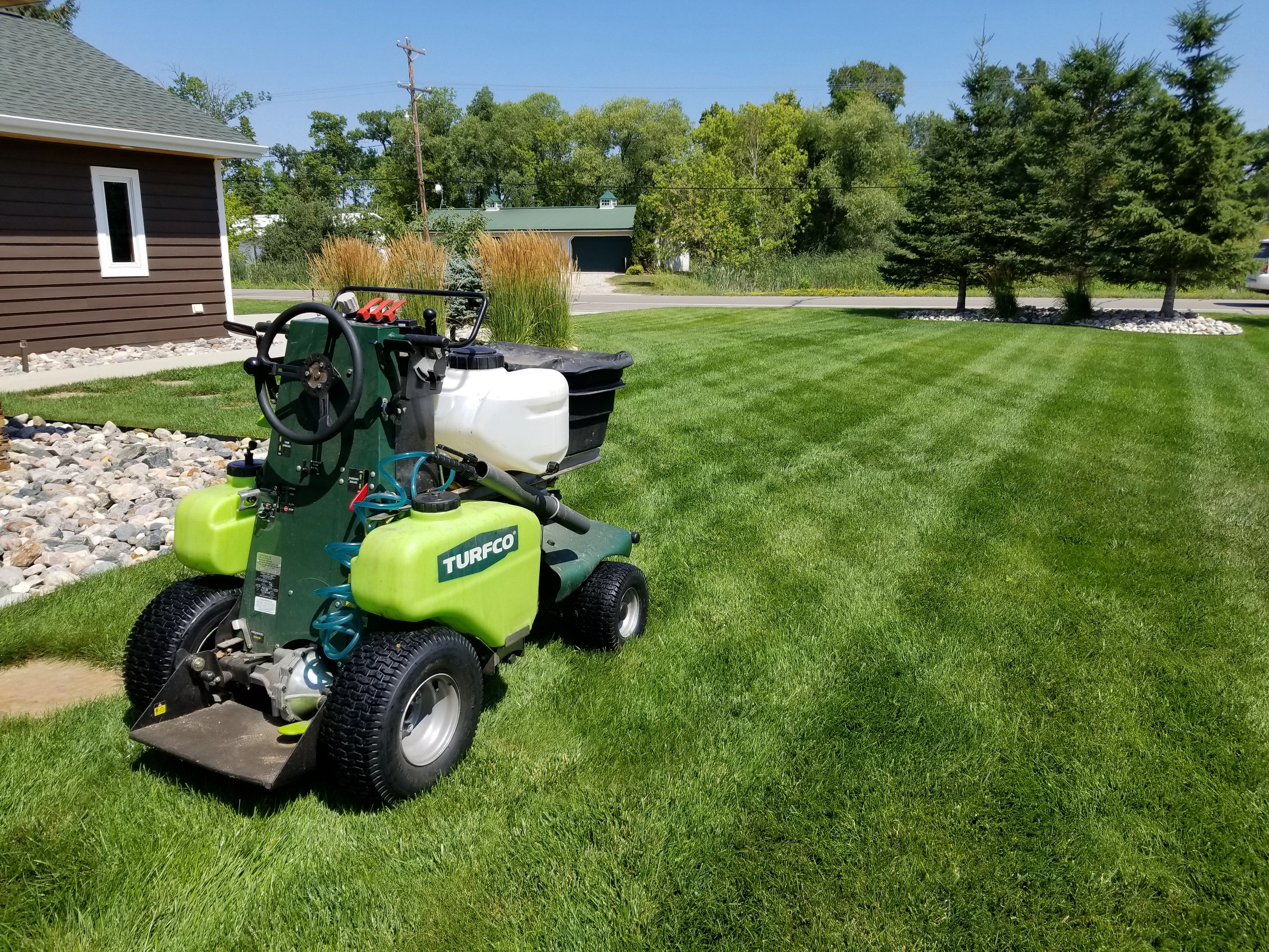 Miller Yard Care & Construction team member applying a fertilization treatment to a lawn in Detroit Lakes, MN.